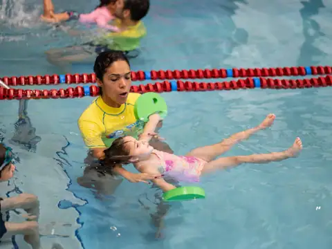 Instructor teaching a child to float on her back